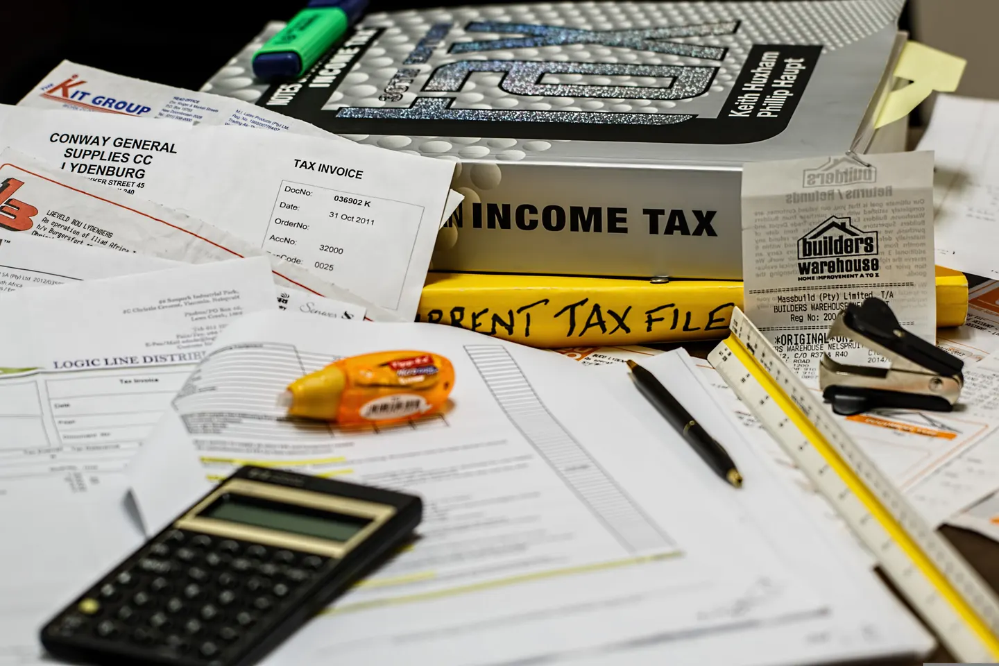 Invoices, receipts, tax books and a calculator arranged on a desk