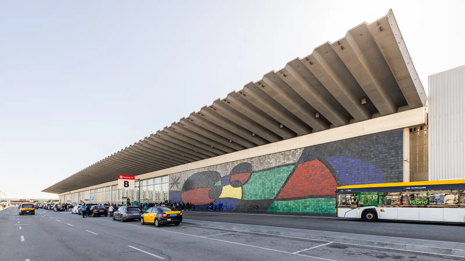 Interior of terminal 2 at Barcelona Airport with check-in counters, travellers and overhead signs.