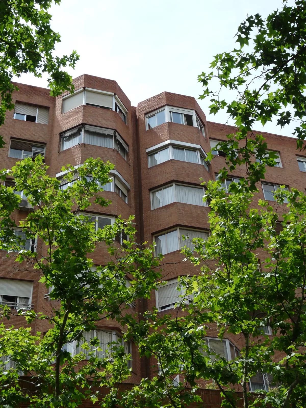 Bloque residencial de ladrillo visto entre árboles en la calle Basílica de Madrid