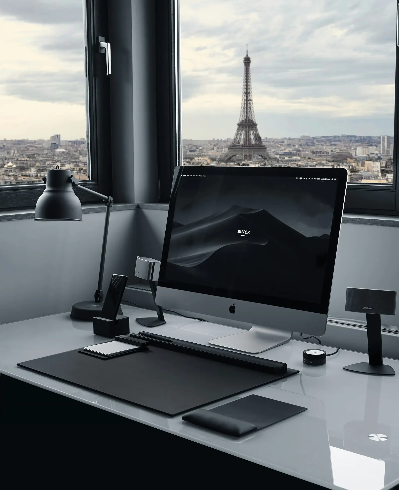 A computer workstation in Paris with the Eiffel Tower visible through the window.