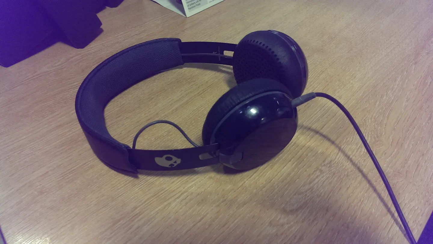 Black over-ear headphones resting on a wooden desk