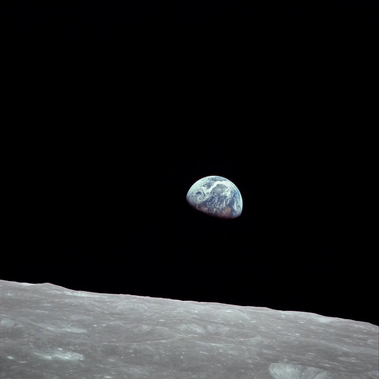 The blue and white Earth above the gray lunar horizon against black space