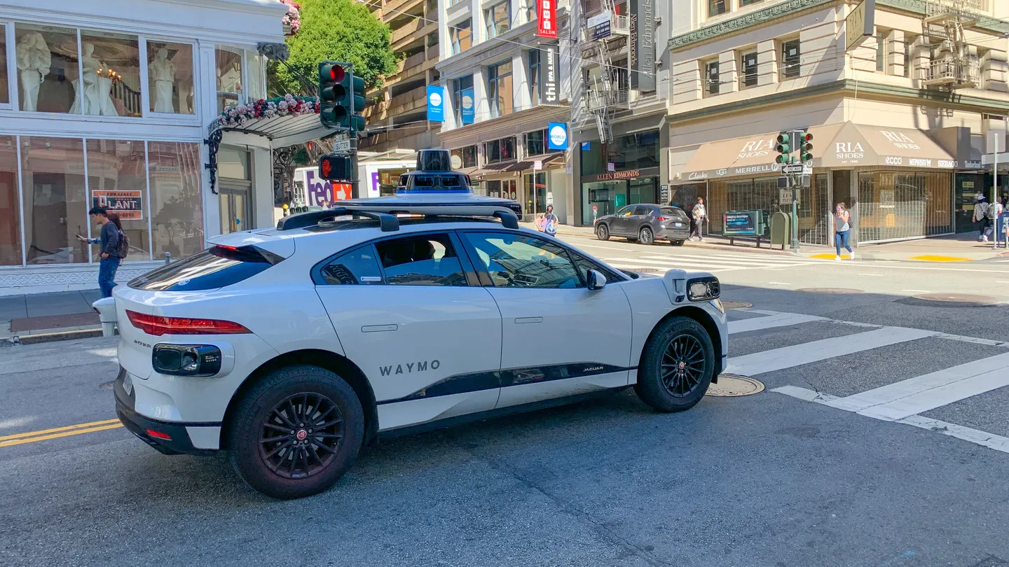 White Waymo Jaguar I-PACE with roof sensors on a San Francisco street