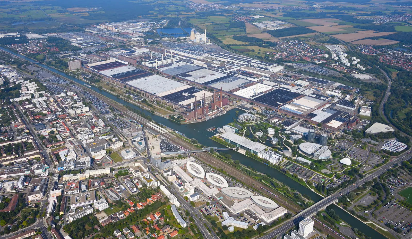 Aerial view of the Volkswagen plant in Wolfsburg, Germany, with production halls, power plant, canal and surrounding city.